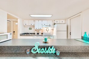 Una cocina con armarios blancos, un microondas, una estufa y un refrigerador.