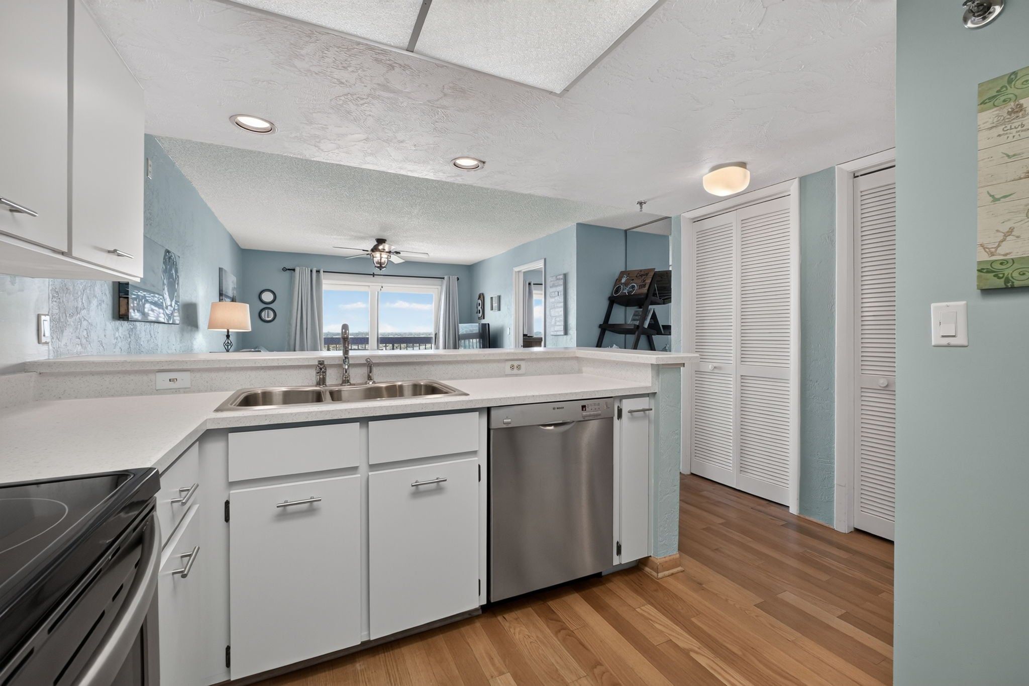 A modern kitchen with a central island, stainless steel appliances, and a view to the outside.
