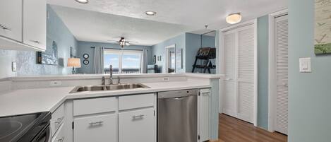 A modern kitchen with a central island, stainless steel appliances, and a view to the outside.