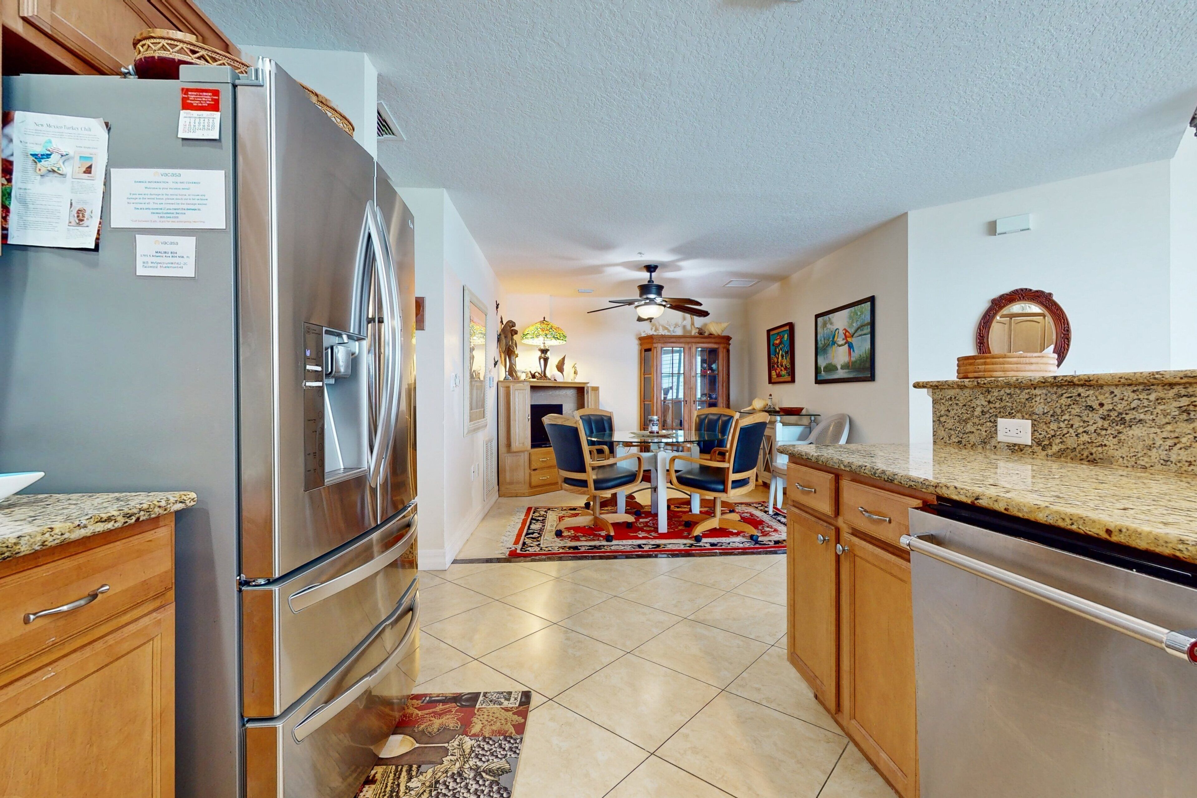 A modern kitchen with stainless steel appliances, wooden cabinets, and a dining area with a glass table and chairs.