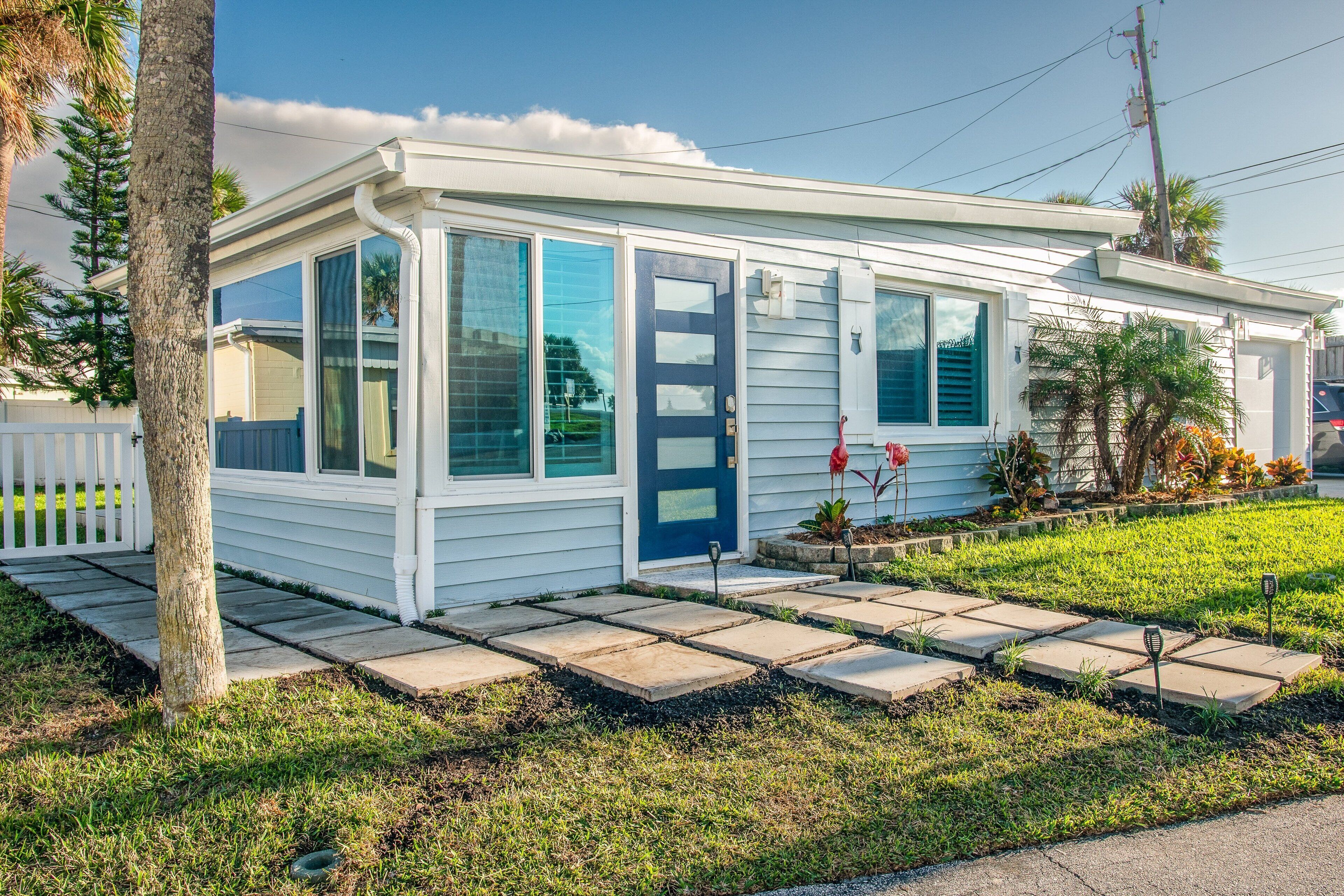 A single-story house with a front porch, a blue door, and a small garden area.