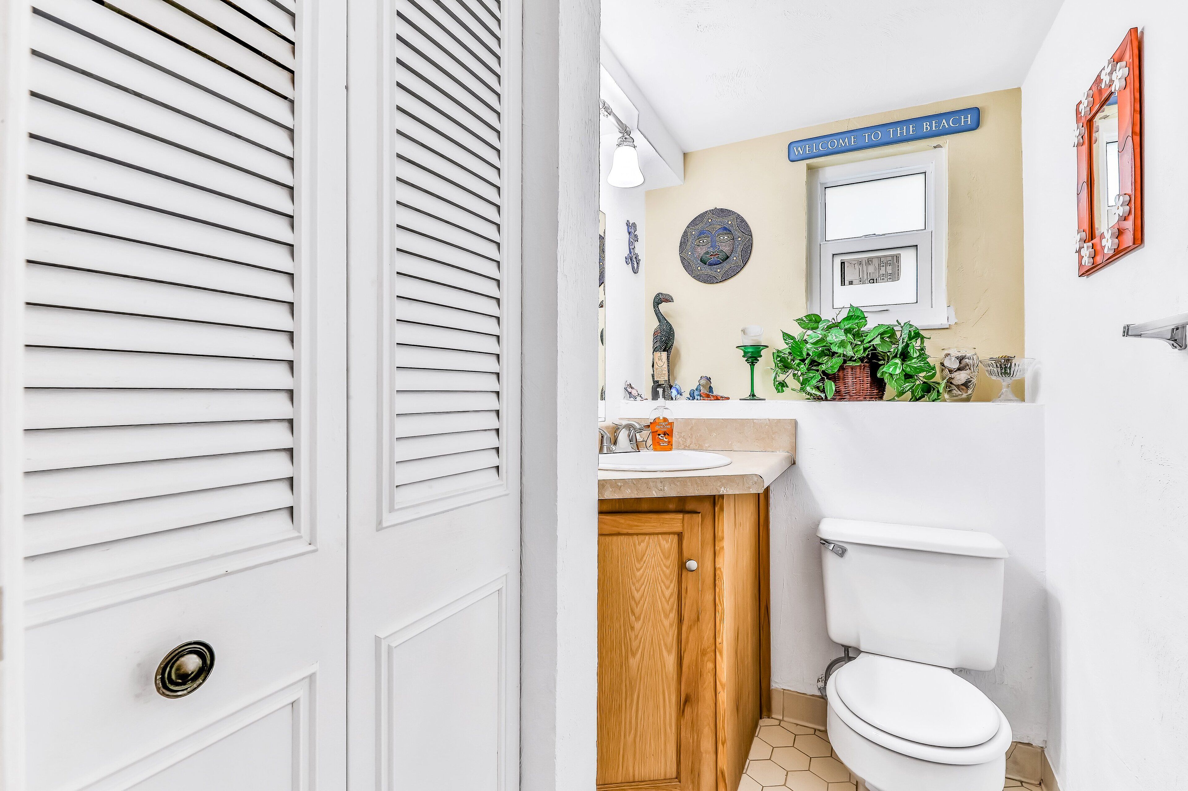 A bathroom with a white toilet, wooden cabinet, and a sink with decorative items.