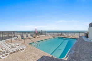 A pool area with lounge chairs and a view of the ocean. - Daytona Atlantico 32 (Daytona Beach)