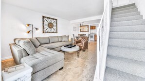 A living room with a sectional sofa, a coffee table, and a staircase. - Daytona Atlantico 32 (Daytona Beach)
