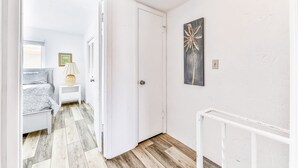 A hallway with a bed, nightstand, and artwork on the wall. - Daytona Atlantico 32 (Daytona Beach)