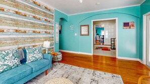 A living room with a blue sofa, a wooden wall, and a chandelier. - Daytona Beach Retreat (Daytona Beach)