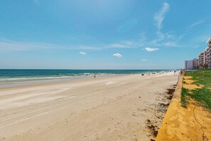 A beach with a clear sky, a sandy shore, and a building with balconies on the right. - Ponce Inlet Villa #4A (Ponce Inlet)