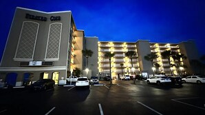 A multi-story hotel with a prominent 'Pirates Cove' sign, a parking lot with several cars, and a well-lit facade. - Daytona Pirates Cove 3270-salt Air Cove (Daytona Beach Shores)