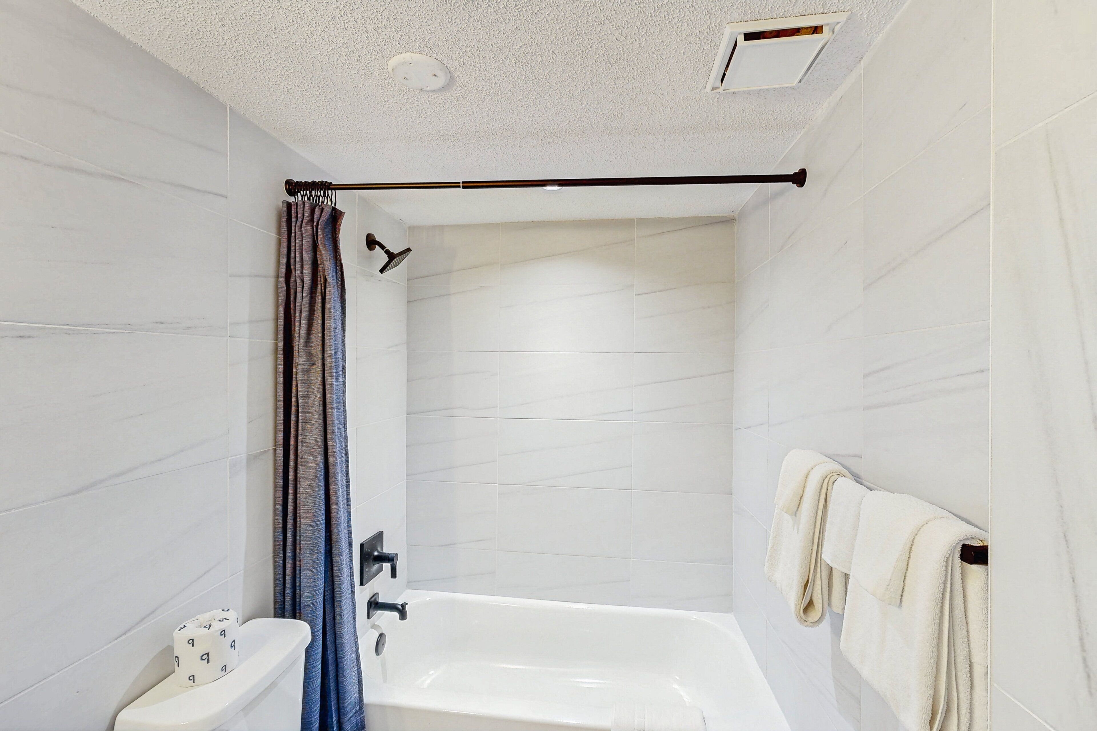 A modern bathroom with a bathtub, a shower curtain, and a towel rack.