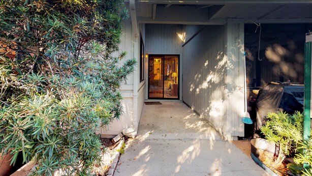 Una casa con un portico coperto, un ingresso che conduce all'interno e piante in vaso disposte intorno.