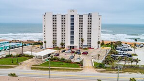 Ein hoch aufragendes Hotel mit Parkplatz und Blick auf den Strand.