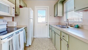 A compact kitchen with a microwave, stove, refrigerator, and sink. - Nsb- Seaside Oasis (New Smyrna Beach)