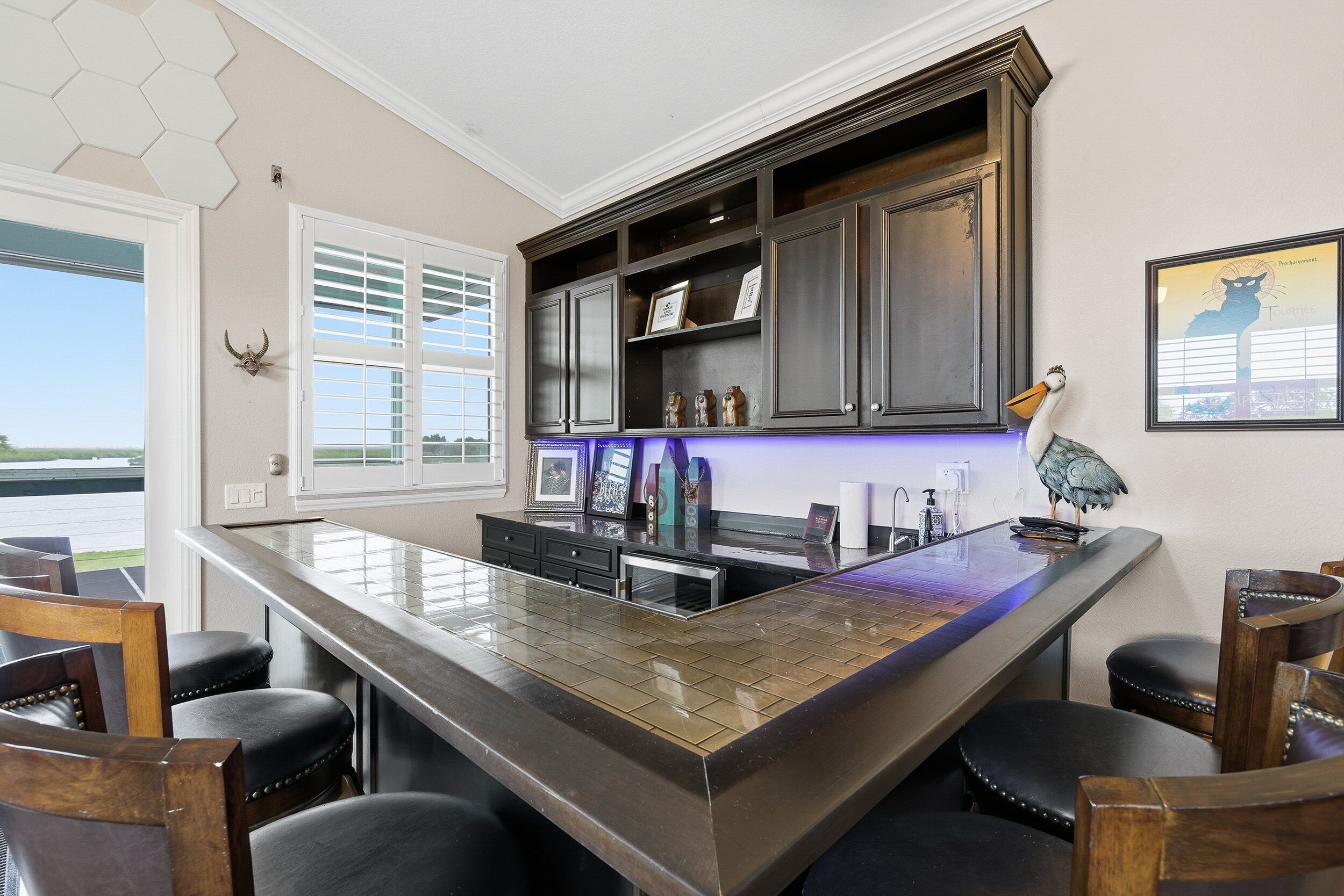 A kitchen with a large island, dark wooden cabinets, and a view of the outdoors.