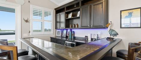 A kitchen with a large island, dark wooden cabinets, and a view of the outdoors.