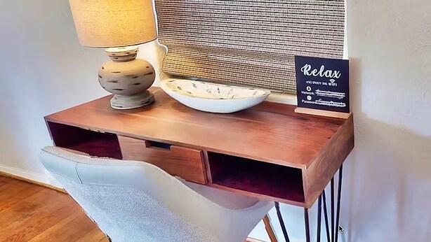 Et træskrivebord med en lampe, en skål og et skilt der står 'Slap af og nyd WiFi'.