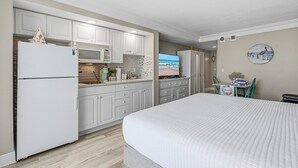 Habitación de hotel compacta con kitchenette, una cama y vista al mar.