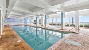 Una piscina interior con agua cristalina, suelo de baldosas y vistas al exterior.