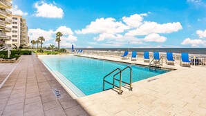 A swimming pool with a clear view of the ocean, a beach, and a hotel building in the background. - Daytona Surfside Club 109- Blue Umbrella (Daytona Beach Shores)