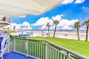 A balcony with a view of the beach, palm trees, and a pool area. - Daytona Surfside Club 109- Blue Umbrella (Daytona Beach Shores)