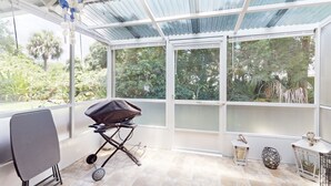 Ein überdachter Patio-Bereich mit Grill, Stuhl und dekorativen Laternen.