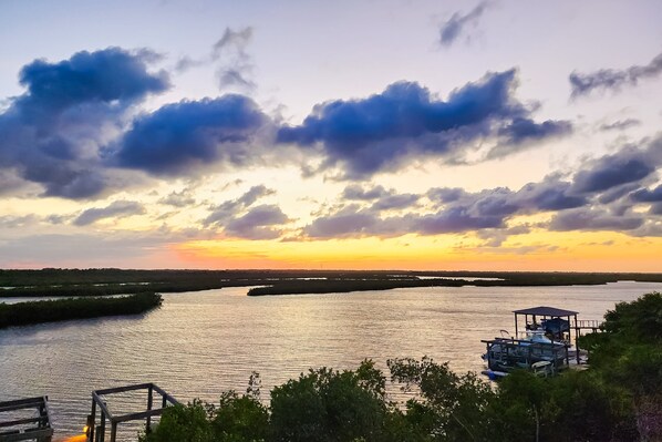 A sunset view over a calm river with a boat dock and a gazebo. - NSB Indian River Waterfront Gem (New Smyrna Beach)