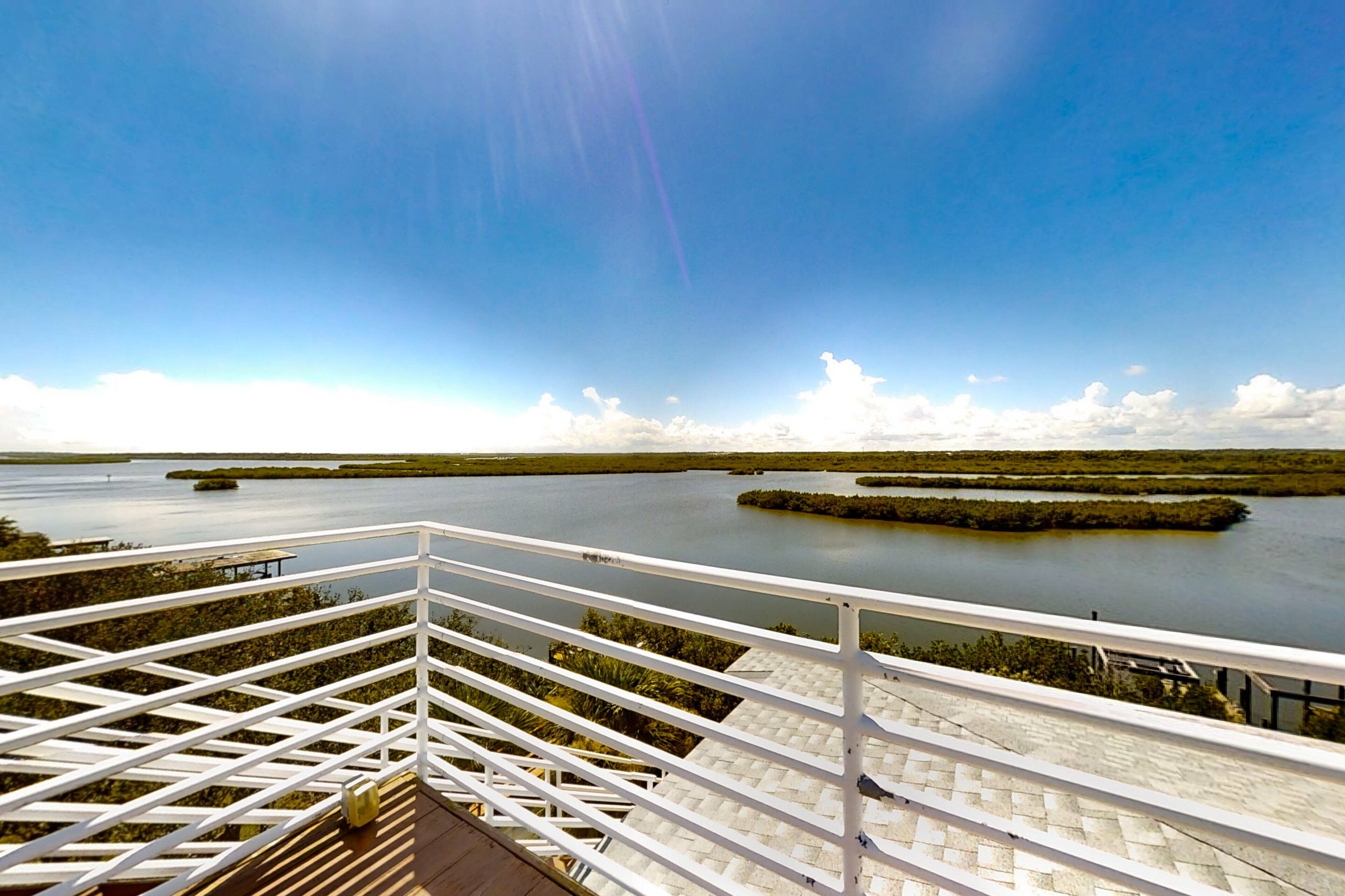 A balcony with a view of a calm water body and distant land.