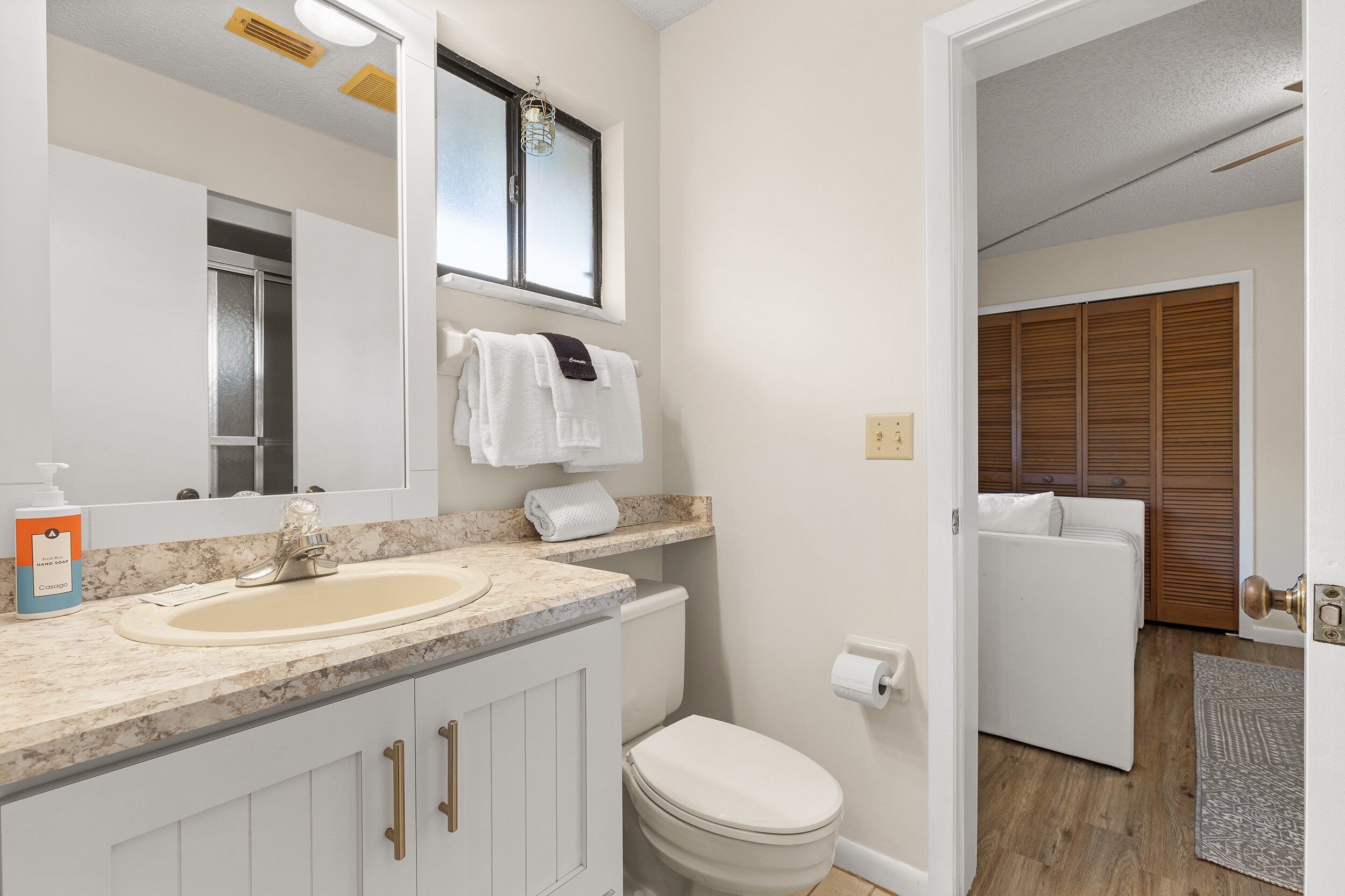 A bathroom with a sink, mirror, towel rack, and toilet.
