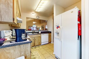 Una cocina con armarios de madera, un refrigerador blanco, una cafetera y un lavavajillas.