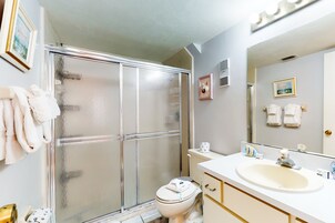 Un baño con ducha acristalada, inodoro, lavabo y espejo.