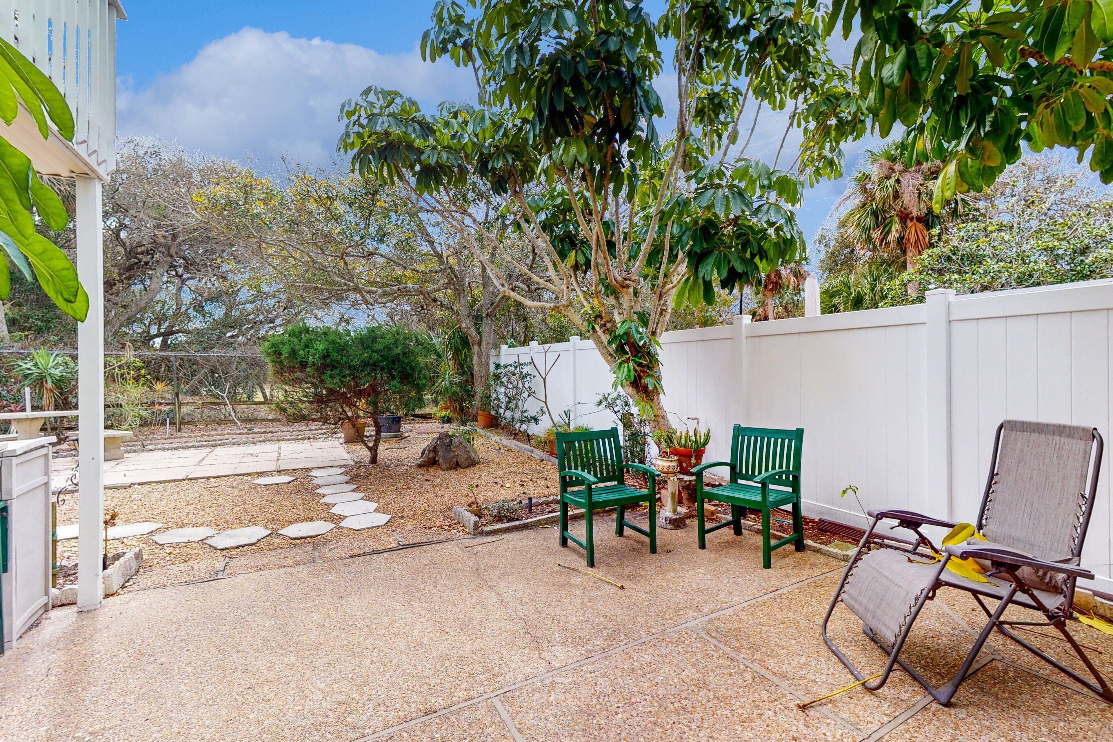 A patio with two green chairs, a folding chair, and a small table.
