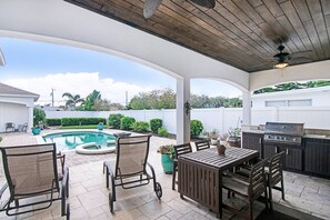 An outdoor patio with a pool, a grill, and seating. - NSB Pearl By The Sea (New Smyrna Beach)