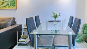 Una sala riunioni moderna con un tavolo in vetro, sedie in pelle nera, un piccolo vaso con fiori e un quadro appeso al muro.