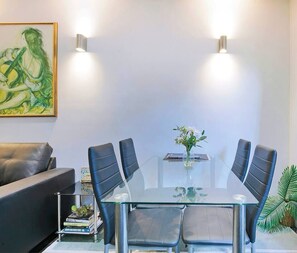 A modern meeting room with a glass table, black leather chairs, a small vase with flowers, and a painting on the wall. - Kelvin Grove Corner Near QUT Campus Dining and CBD (Red Hill)