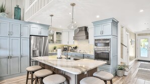 Una cucina moderna con mobili azzurri, elettrodomestici in acciaio inossidabile e un'isola in marmo con sgabelli da bar.