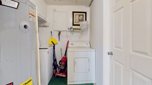 A laundry room with a washing machine, dryer, and vacuum cleaner. - Seaside Escape (Ormond Beach)