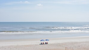 A beach with two blue umbrellas and two beach chairs. - Smyrna Beach Club 307 (New Smyrna Beach)