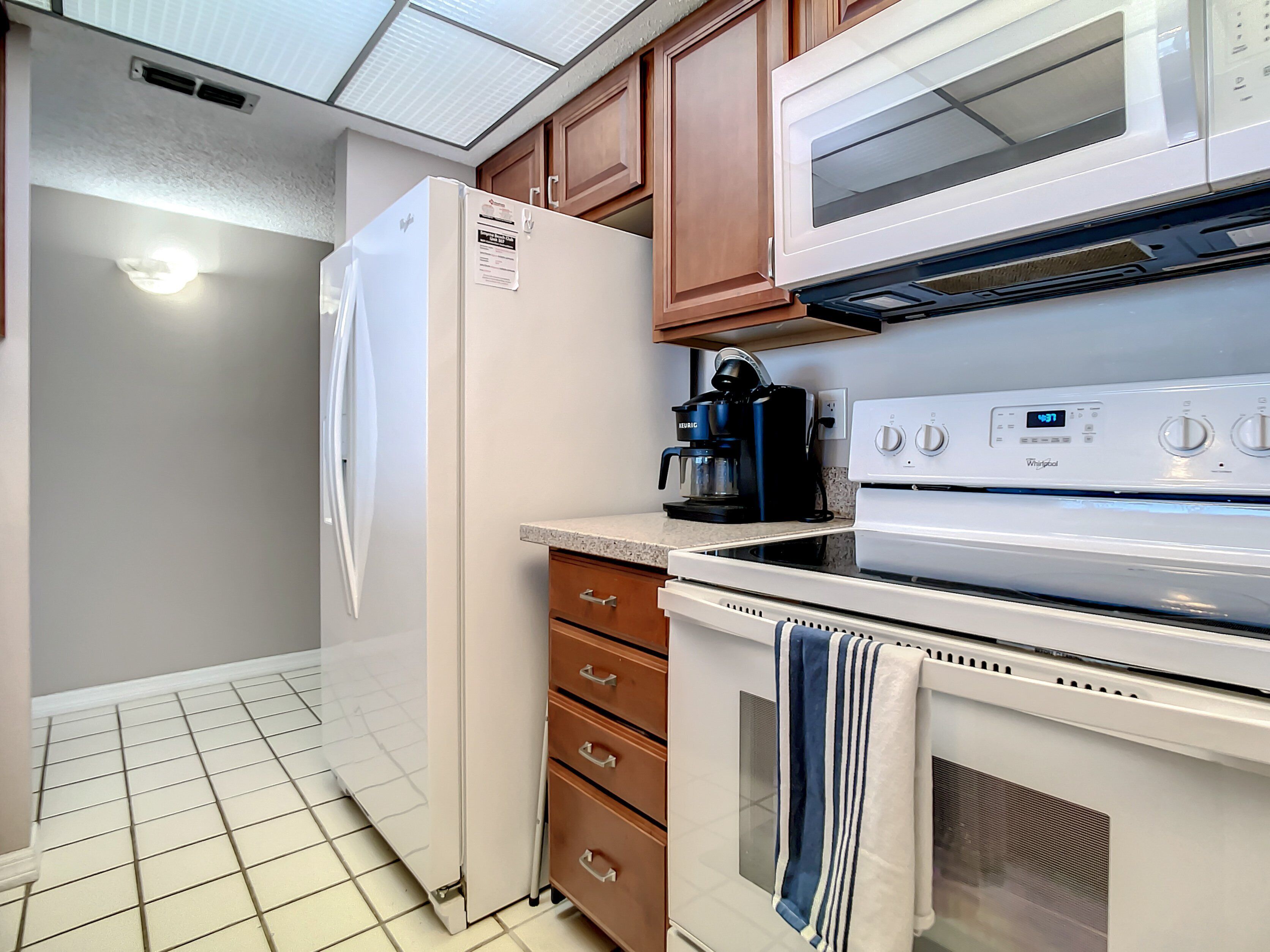 A kitchen with a refrigerator, microwave, stove, and coffee maker.