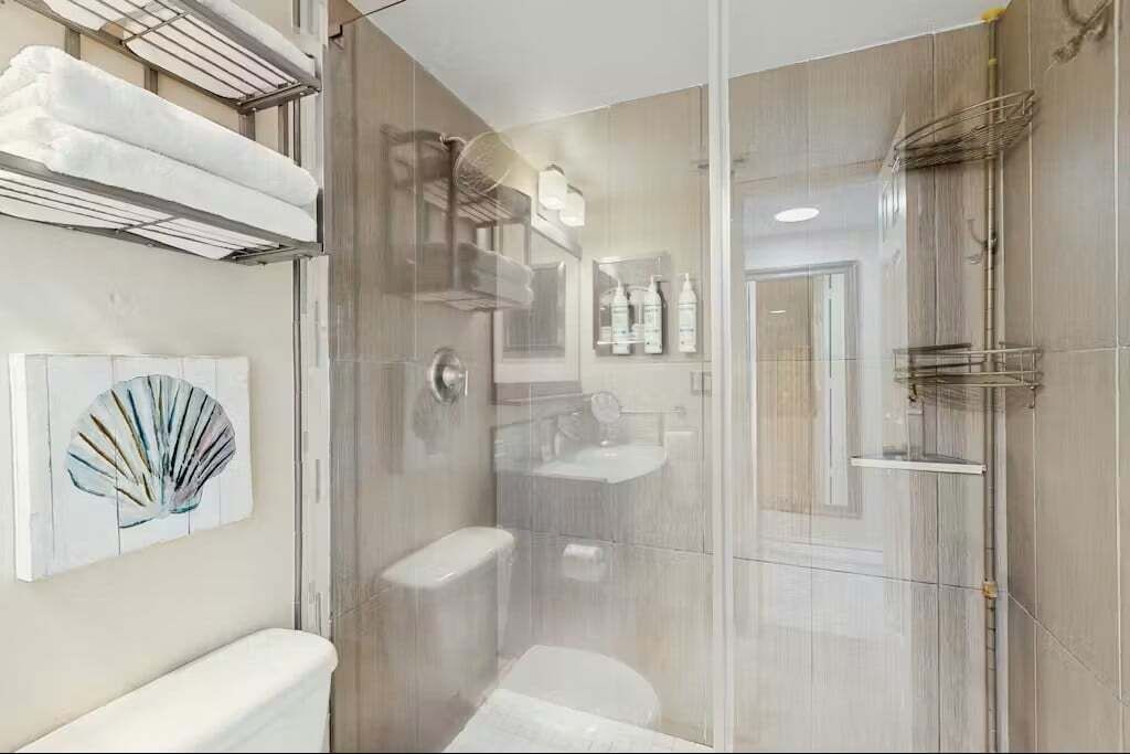 A modern bathroom with a glass-enclosed shower, a toilet, and a sink.
