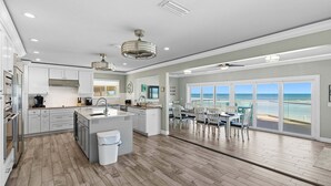A modern kitchen with a central island, a dining area with a view, and a large window overlooking the ocean. - Atlantic Sunrise Home Plus Cottage (Daytona Beach Shores)