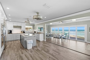 Una cocina moderna con una isla central, un comedor con vistas y un amplio ventanal con vista al océano.