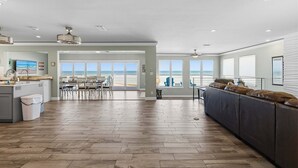 A spacious living area with a large window, a kitchen, and a seating area. - Atlantic Sunrise Home Plus Cottage (Daytona Beach Shores)