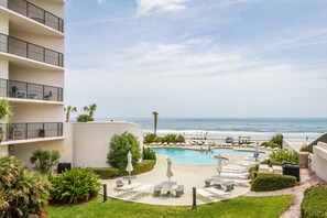Un hotel con piscina, asientos al aire libre y vista al océano.