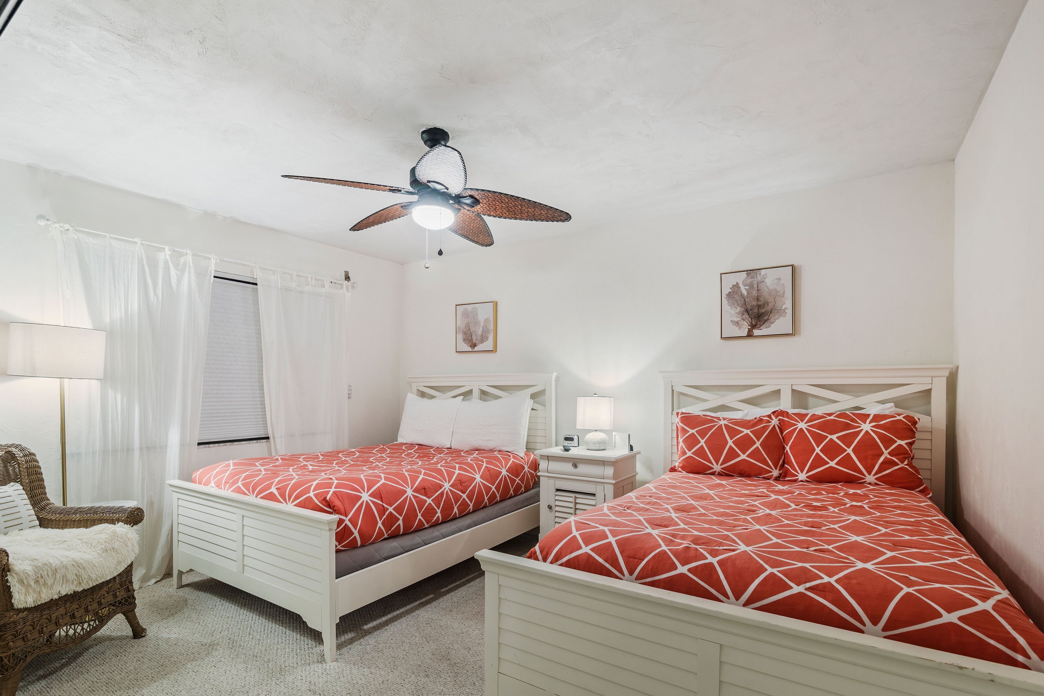 A bedroom with two beds, a ceiling fan, a nightstand, a lamp, and a chair.