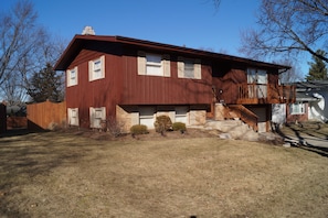 A two-story house with a wooden deck and a front porch.