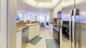 A modern kitchen with stainless steel appliances, white cabinetry, and a central island. - Daytona Grande Towers - Ocean Paradise 702 (Daytona Beach Shores)