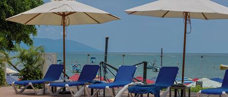 A poolside area with lounge chairs and umbrellas, overlooking a body of water.