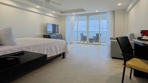 Una habitación de hotel moderna con una cama, un escritorio, una silla, un televisor y un balcón con vistas.