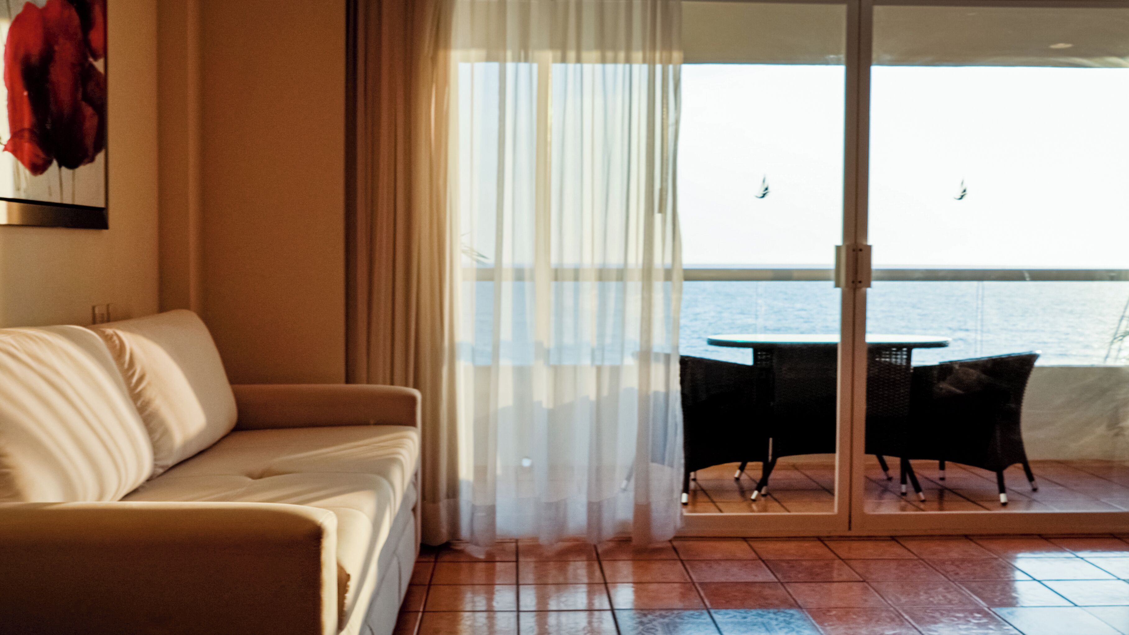 A balcony with a sofa and a table, overlooking a body of water.