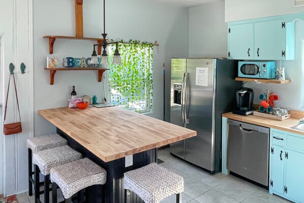 A kitchen with a wooden island, stainless steel appliances, and light blue cabinets. - Edgewater- River Cottage (Edgewater)