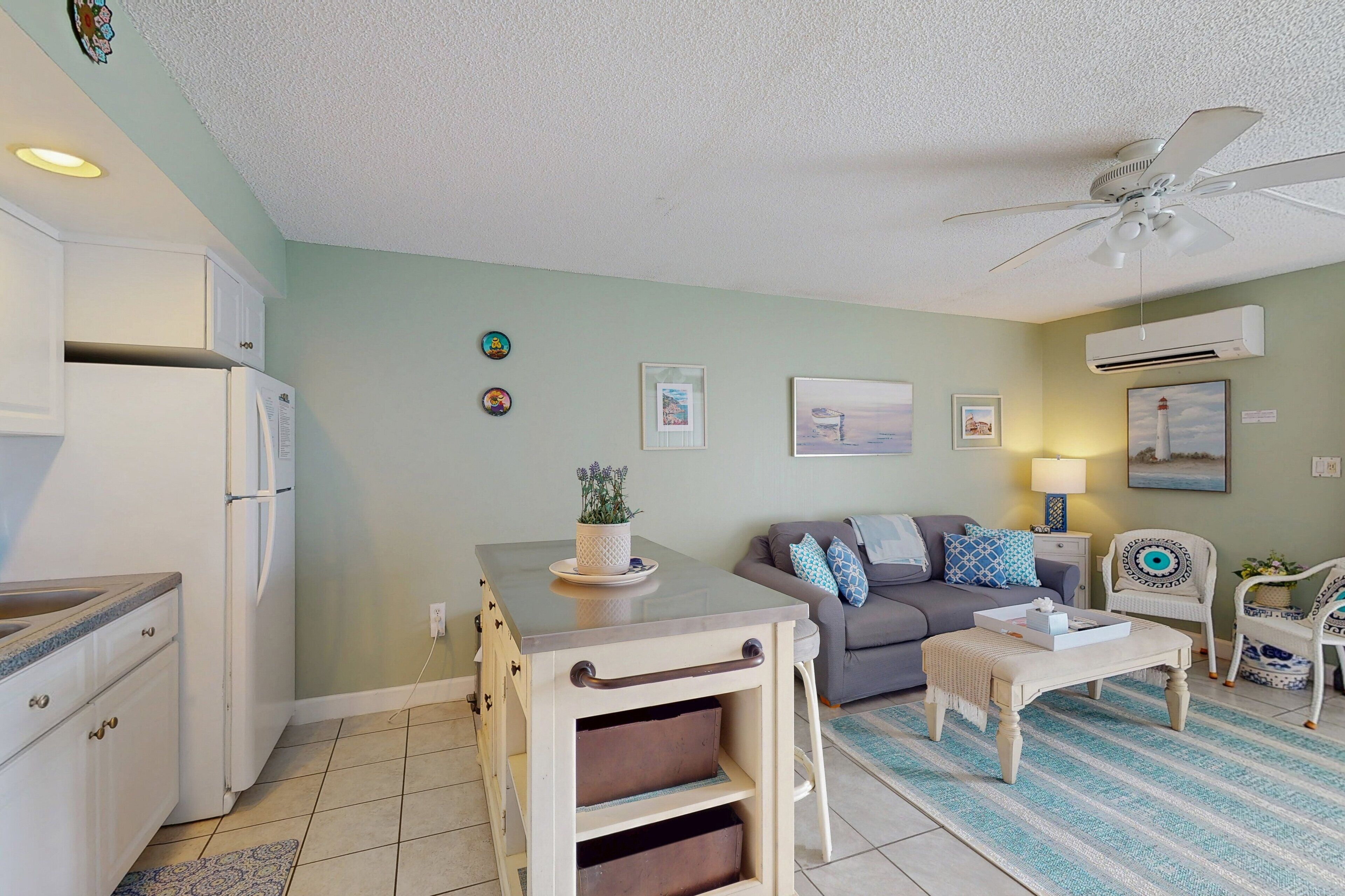 A compact living space with a kitchenette, a sofa, a coffee table, and a ceiling fan.